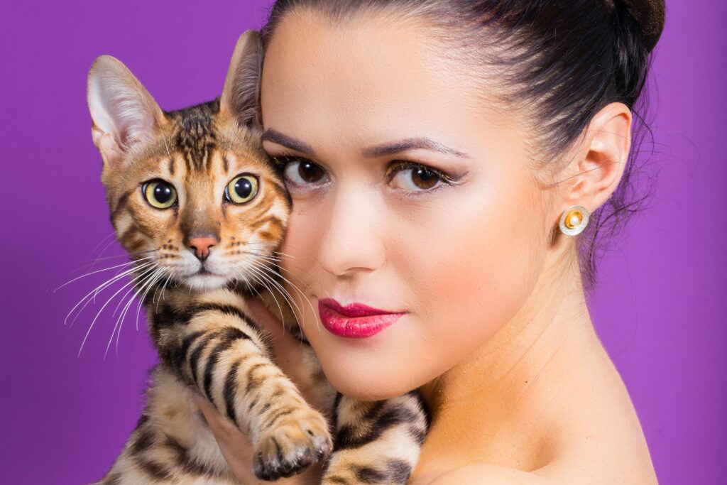 A woman is holding a bengal cat